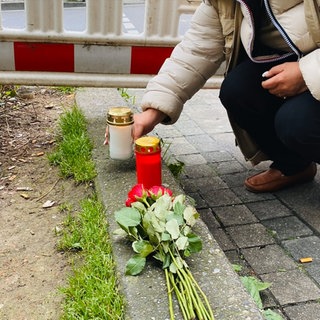 Menschen legen am Tag nach dem Unfall Blumen am Unfallort am Olgaeck ab oder stellen Kerzen auf.