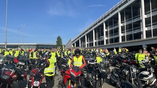 Mehrere Motorradfahrerinnen und -fahrer warten auf den Start des Korsos.