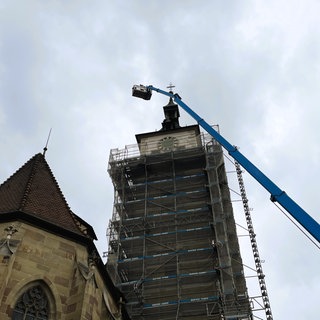 Eine Hebebühne wird an einem Kirchturm hochgefahren.