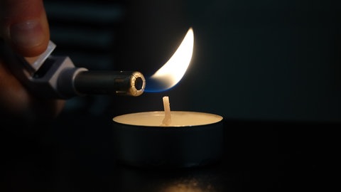 Eine Kerze wird mit einem Feuerzeug angezündet. (Symbolbild)