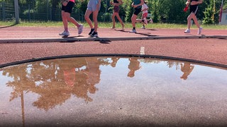Auf einer Laufbahn auf der Waldau laufen Schülerinnen ein Rennen. 