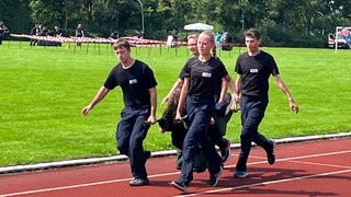 Polizei-Challenge in Göppingen: Jugendliche tragen eine Person über einen Sportplatz