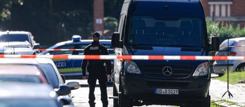 Ein Kastenwagen der Polizei mit einem Ermittler und Polizeiabsperrband (Symbolbild). Ende August hat ein Bauhof-Mitarbeiter in Bonladen-Filderstadt eine Leiche gefunden. Die konnte mittlerweile identifiziert werden.