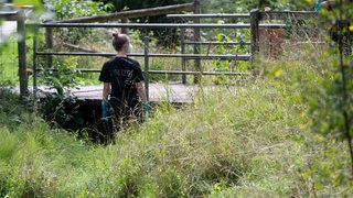 Eine Polizistin stehen an einer Brücke am Stadtrand von Filderstadt. In Filderstadt wurde ein Koffer mit einer Leiche darin unter einer Brücke an einem kleinen Bachlauf gefunden.