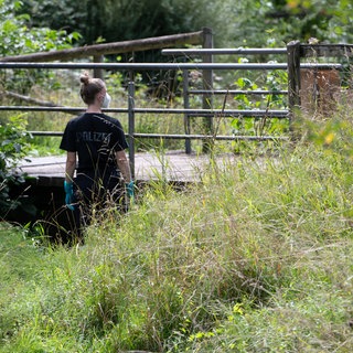 Eine Polizistin stehen an einer Brücke am Stadtrand von Filderstadt. In Filderstadt wurde ein Koffer mit einer Leiche darin unter einer Brücke an einem kleinen Bachlauf gefunden.
