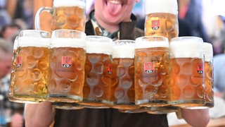 Ein Kellner trägt bei der Eröffnung des Cannstatter Wasen mehrere Bierkrüge. 