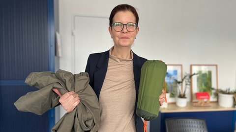 Svenja Gruß vom katholischen Sozialdienst zeigt eine Isomatte und einen wasserabweisenden Biwak-Sack, den ein Mann aus Bonn für "Schwalbe" geschickt hat.