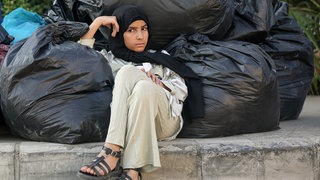 Die syrische Geflüchtete Hasna sitzt neben ihren Habseligkeiten, während sie mit ihrer Familie darauf wartet, Beirut zu verlassen. 