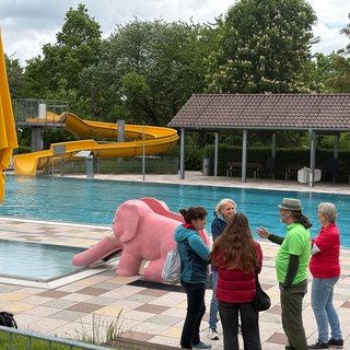 Freibadverwalter Andreas Gölz steht mit Ehrenamtlichen und Badebesuchern vor dem Schwimmbecken des ASV-Freibads Botnang.