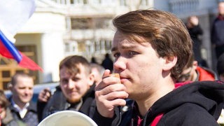 Gleb hat ein Megafon in der Hand bei einer Demonstration in Russland