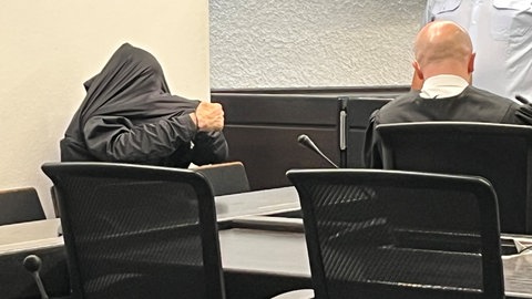Angeklagter im Kofferleichen-Prozess zieht sich im Gerichtssaal Jacke über den Kopf.