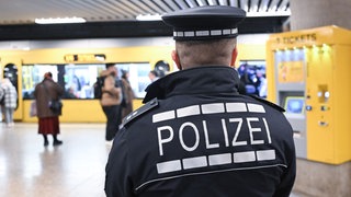 Polizist steht mit Rücken zur Kamera an Stadtbahnhaltestelle Charlottenplatz