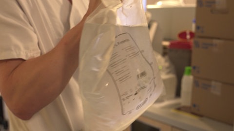 Ein Mann hält einen Beutel voller gekühlter Flüssigkeit in der Hand.