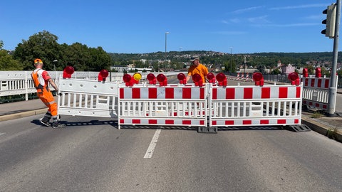 Männer schleppen Absperrungen auf eine Brücke.