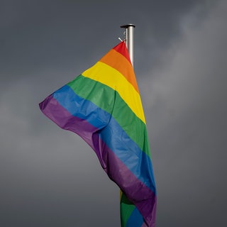 Eine Regenbogenflagge vor dunklen Wolken