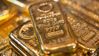 Goldbarren liegen in einem Tresor auf einem Tisch.