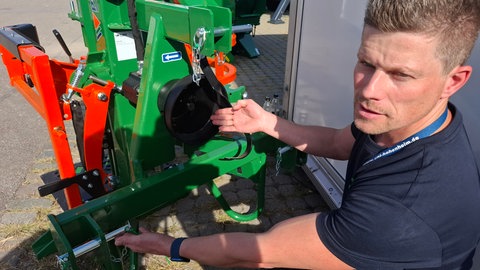 Daniel Wolpert demonstriert an einem Holzspalter auf dem Landwirtschaflichen Hauptfest in Stuttgart, wo der "AgriBoost" ansetzt: Er kann per Dreipunktaufhängung hinten am Traktor angebracht werden und über die Zapfwelle elektrisch die Landmaschine antreiben, beziehungsweise den Betrieb über den Dieselmotor unterstützen.