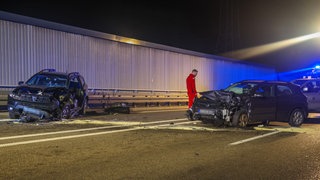 Zwei schwer beschädigte Autos stehen nach einem Unfall auf der Straße.