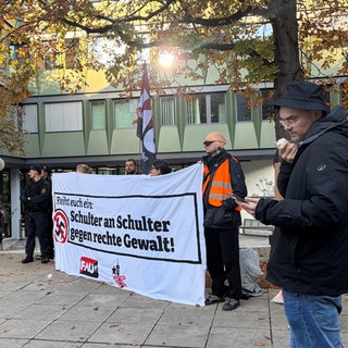 Mehrere Mitglieder der linksextremen Gewerkschaft FAU stehen mit einem Protestplakat vor dem Landgericht Stuttgart.
