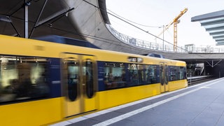 Eine gelbe Stadtbahn kommt aus einem Tunnel.