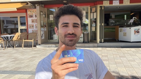 Mohamad Sami Dabbas hält seine Bezahlkarte in die Kamera. Der Asylbewerber ist vom System mit der Karte genervt.