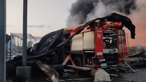 In der Ukraine steht vor Bombentrümmern und Rauch ein zerstörtes Feuerwehrfahrzeug. Das soll durch eines aus Dettingen an der Erms ersetzt werden.