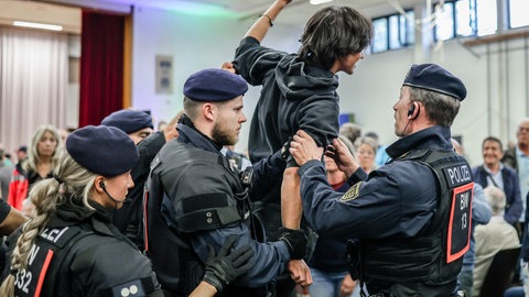 Polizisten führen Personen aus der Hermann-Hepper-Halle in Tübingen.