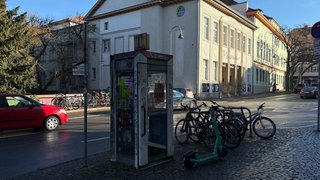 Beklebte und beschmierte Telefonzelle am Straßenrand.