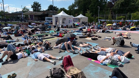 Mehrere hundert Menschen liegen auf Isomatten, Feldbetten und Picknickdecken mitten auf dem Tübinger Europaplatz. Sie demonstrieren für mehr Aufmerksamkeit für MECFS Erkrankte.