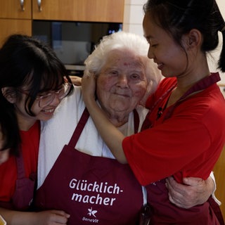 Zwei junge Frauen umarmen eine alte Dame im Pflegeheim. Die Frauen aus Myanmar machen in Mössingen bei BeneVit eine Ausbildung zur Pflegerin.