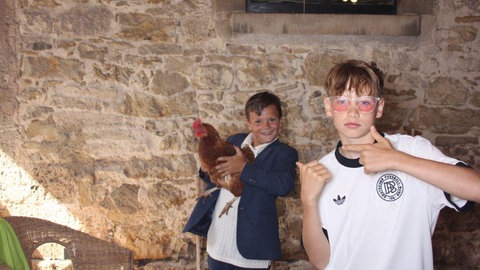 Kinder und Hühner sind gemeinsam in einer Fotobox bei einer Hochzeit auf dem Hofgut.