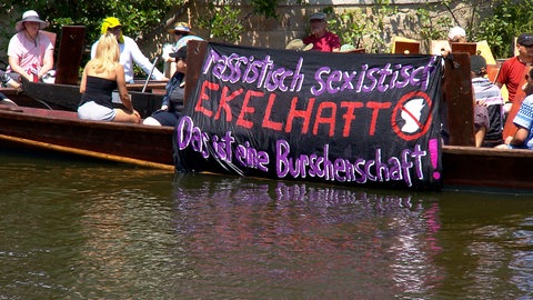 Der feministische "Flinta-Kahn" protestiert mit Bannern auf dem Neckar gegen das Stocherkahnrennen. 