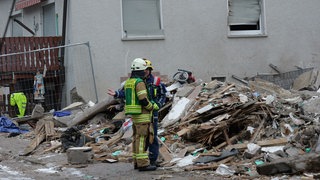 Zwei Feuerwehrmänner stehen vor dem explodierten Haus in Albstadt-Tailfingen. Fünf Monate nach der Gasexplosion hat die Staatsanwaltschaft die Ermittlungen abgeschlossen.