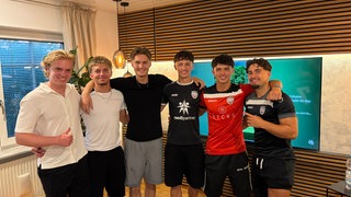 Fußballer MAxim Schmalz in der Mitte zwischen seinen Kumpels, alle Arm in Arm.