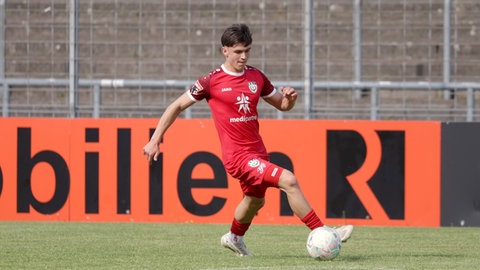 Fußballspieler Maxim Schmalz beim Spiel auf dem Fußballrasen. Er ist am Ball.