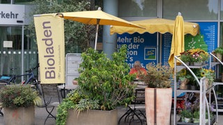 Der Tübinger Marktladen: Davor sind Sonnenschirme aufgespannt und ein Schild mit der Aufschrift "Bioladen" ist zu sehen. Bioläden geraten immer mehr unter Druck.