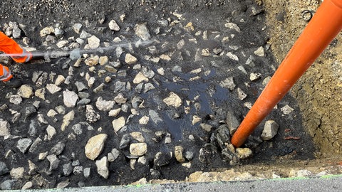 Ein Stadtgärtner gießt einen mit Schotter versetzen Boden in der Kaiserstraße in Reutlingen. Dort entstehen Baumquartiere nach dem "Stockholmer Modell".