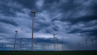 Dunkle Gewitterwolken ziehen am späten Abend über einen Windenergiepark.Das Unternehmen SOWITEC ist nach eigenen Angaben insolvent.