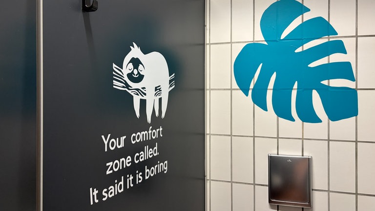 In einer Klokabine klebt ein Sticker eines Faultiers. Schüler des Carlo-Schmid-Gymnasiums in Tübingen übernehmen die Gestaltung ihrer Schultioletten selbst.