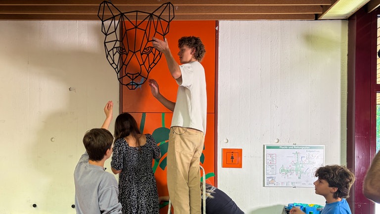 Schüler bringen über der Klotür einen gedruckten Pantherkopf an. Schüler des Carlo-Schmid-Gymnasiums in Tübingen übernehmen die Gestaltung ihrer Schultioletten selbst.
