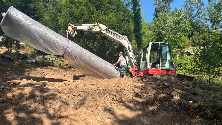 Mit dem Bagger bewegen die Handwerker die 300 Kilo schweren Röhren