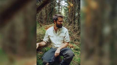 Mykologe (Pilz-Experte) Flavius Popa kniet im Schwarzwald. Dort erforscht er unter anderem, wie Pilze mit der Trockenheit umgehen