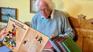 Mann hält altes Comicheft von Micky Maus in der Hand. Er ist ein großer Fan.