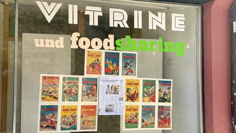 Kopien der ersten Micky Maus Zeitschriften hängen im Schaufenster eines Foodsharing Verteilers. Ernst Heimes hat sie aufgehangen, um das 75 Jährige Jubiläum zu feiern.