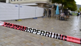 Ein Absperrband der Polizei markiert den abgesperrten Bereich zu einem Schusswechsel in einer Fußgängerzone nahe dem Rathaus.