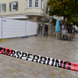 Ein Absperrband der Polizei markiert den abgesperrten Bereich zu einem Schusswechsel in einer Fußgängerzone nahe dem Rathaus.