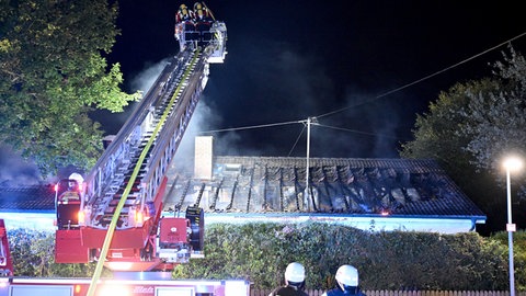Feuerwehrleute löschen von einer Drehleiter aus ein Feuer im Dachstuhl. Der Brand zerstört das Einfamilienhaus in Merklingen. Die Familie, die darin wohnte, war nicht zuhause. 