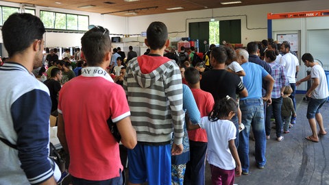 Eine Menschenschlange in einer Halle: Im August 2015 warten Geflüchtete in der Landeserstaufnahmeeinrichtung in Ellwangen auf die Essensausgabe. Zu dieser Zeit leben mehr als 3.000 Flüchtlinge in der LEA, das Dreifache der ursprünglich vereinbarten Maximalbelegung. 