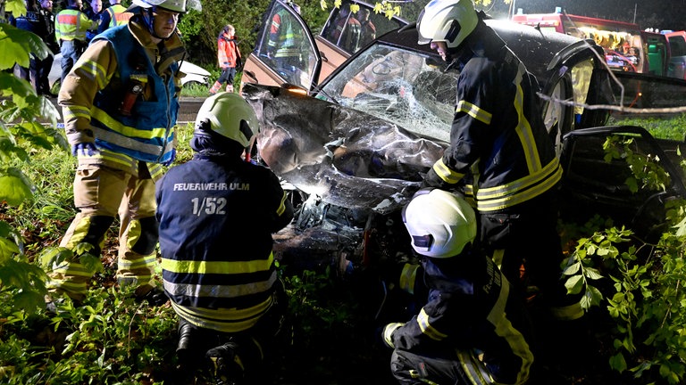 Einsatzkräfte vor einem verunglückten Fahrzeug - bei einem schweren Unfall in Ulm kamen vier Menschen ums Leben.