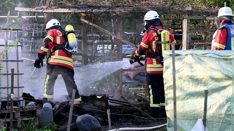 Feuerwehrleute löschen einen der sieben Brände in der Kleingartenanlage in Langenau. Die Polizei ermittelt wegen Brandstiftung. 